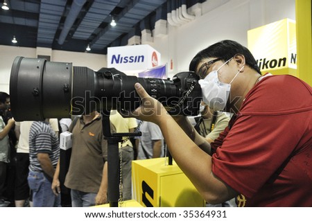 KUALA LUMPUR, MALAYSIA - AUGUST 15: A visitor who wear face mask testing Nikon\'s camera and lens at Kuala Lumpur Photography Festival August 15, 2009 in Mid Valley Exhibition Center, Kuala Lumpur.