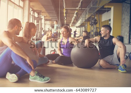 Group of people workout in healthy club. People having conversation after Pilates exercise with Pilates ball.