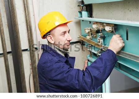 One machinist worker at work adjusting elevator mechanism of lift with spanner