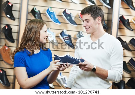 Young man and woman assistant choosing footwear during shopping at shoe shop
