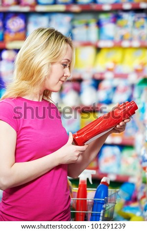 Happy smiling woman choosing personal care items and goods in front of household chemistry produces in shopping supermarket