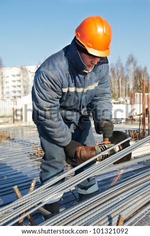 Authentic worker builder with grinding machine cutting reinforcement rods elements for concrete pouring at construction building area site
