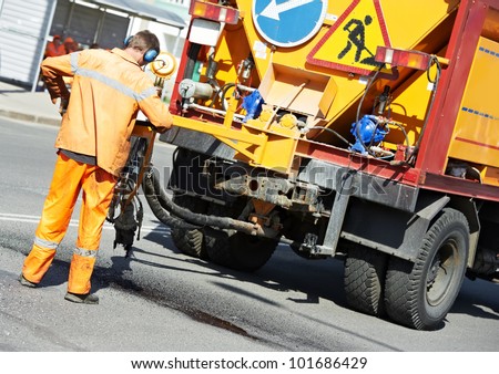 Road worker at asphalt roadway street patching reaparing work