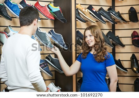 Young man and woman assistant choosing footwear during shopping at shoe shop