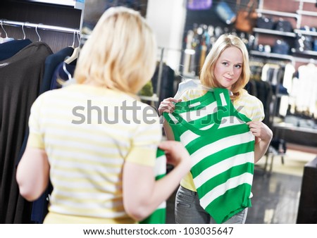 Young woman choosing raincoat outerwear during clothing shopping at apparel store