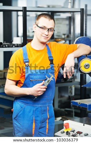 mechanical technician near cnc milling machine center at tool workshop with caliper