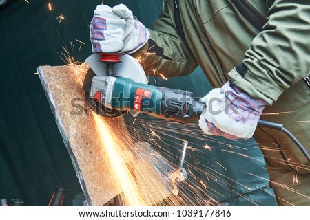 worker grinding cutting metal sheet with grinder machine and sparks