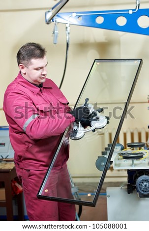 glazier worker with suction cup holding glass at double glazing window manufacture