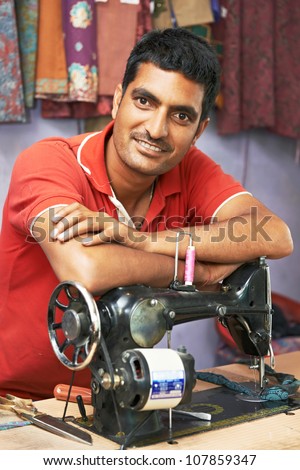 Portrait of indian man tailor at work place with sewing machine