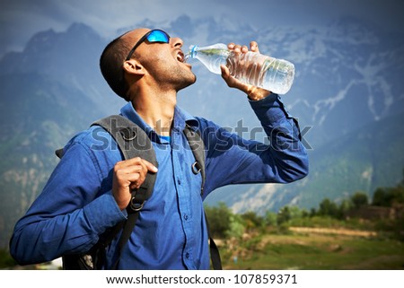 Thirsty traveller in Himalayas mountains drinking pure fresh water from bottle