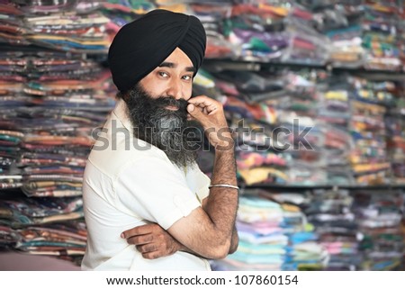 Portrait of Indian sikh man seller in turban with bushy beard at shop