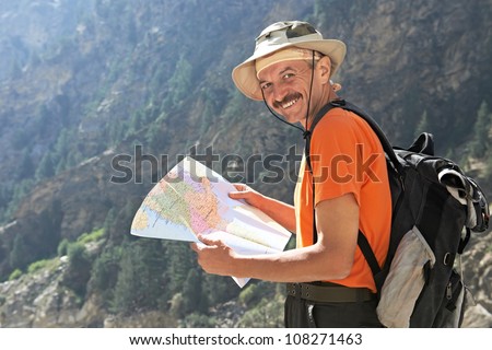 One smiling happy tourist traveller hiker with route map in Himalayas mountains