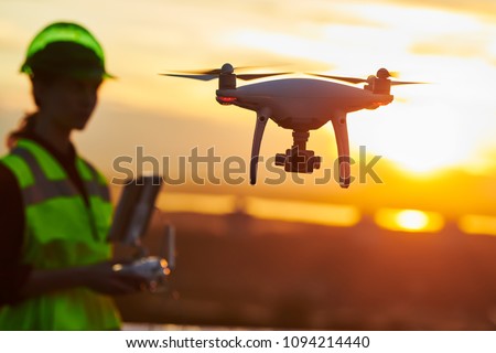 Drone inspection. Operator inspecting construction building site flying with drone. sunset