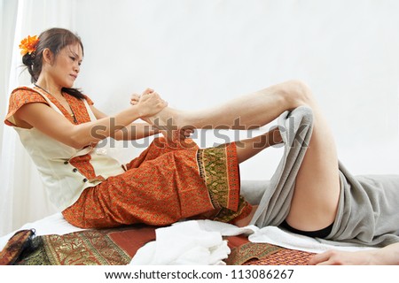 Traditional thai massage health care procedure, kneading foot and leg muscules of man