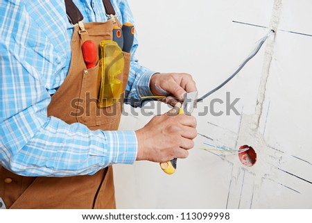 Close-up of electrician worker hands at wiring cable and light switch or power wall outlet socket installation work