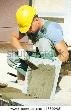 mason worker tiler making stairway from granite stone tile blocks