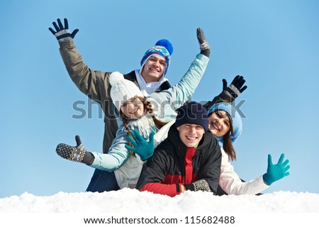 happy young smiling student people group in warm clothing lying on snow at winter outdoors
