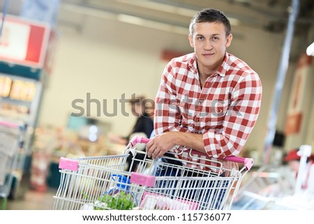 man with shopping cart with food produces in supermarket