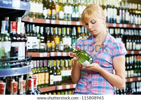 woman choosing bottle of wine in alcohol shopping mall supermarket