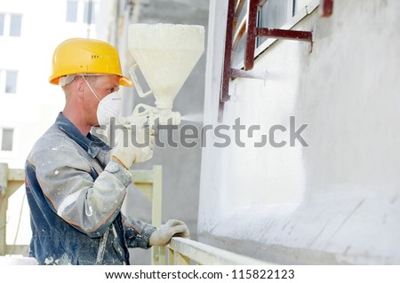 Plasterer facade builder worker with level at thermal insulation works
