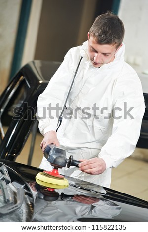 auto mechanic worker polishing car bonnet with wiper at automobile repair and renew service station shop
