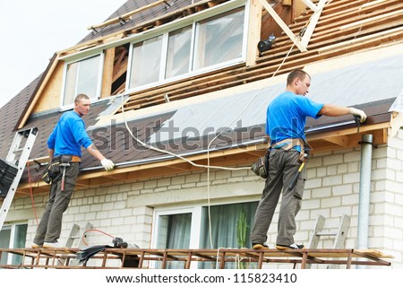 two workers on roof at works with flex tile material measuring roofing drain distance