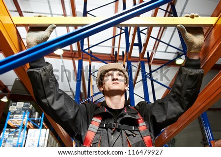 One warehouse worker in uniform with level examining quality of rack installation
