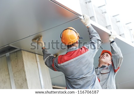 The Workers builders doing facade works with metal sheet boarding