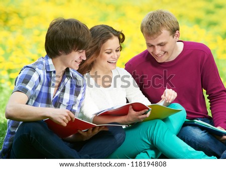Group of three young students studying with note books in spring outdoors