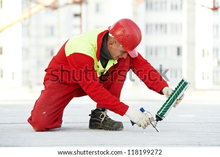 builder filling joint of concrete board with industrial polyurethane sealing foam in protective workwear at construction area