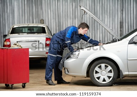 motor mechanic diagnosing automobile car engine before maintenance at repair service station