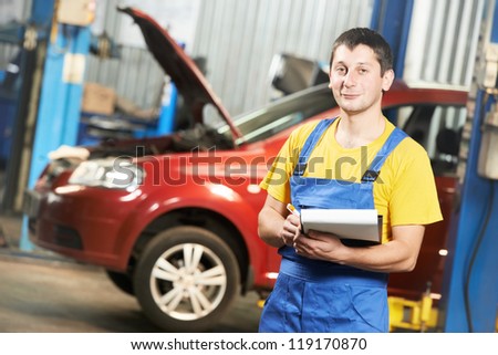repairman auto mechanic with clipboard in front of modern car during automobile maintenance at engine auto repair shop service station