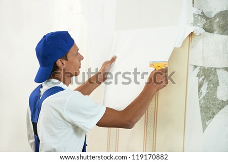 One painter worker peeling off wallpaper during interior home repair renovation work