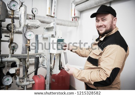 heating engineer or plumber inspector in boiler room taking readouts or adjusting meter