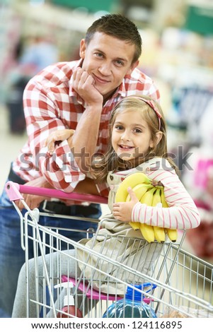 Family food shopping. Young man father and little girl daughter on trolley cart in supermarket