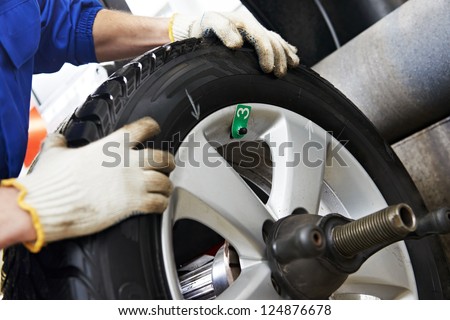 Close-up of mechanic repairman hands during balancing automobile car wheel on balancer