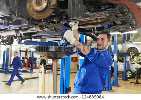Car Mechanic With Spanner Tighten Car Suspension Detail Of Lifted Automobile At Repair Service Station