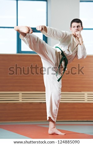 young adult man in kimono training taekwondo martial art at gym