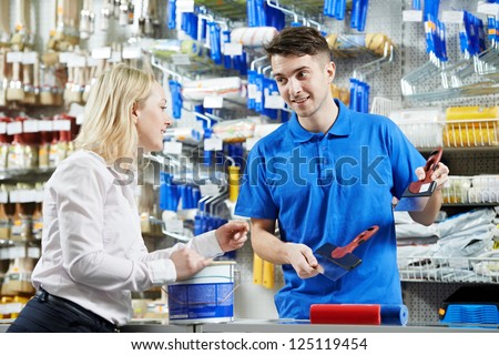 Assistant seller help buyer by demonstrating putty knife for filling at hardware store
