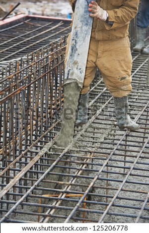 builder worker with tube from truck mounted concrete pump pouring cement into formwork reinforcement