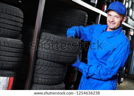 Tyre replacement. mechanic holding tire in store warehouse
