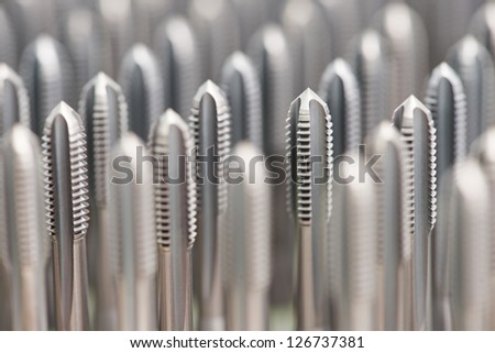 heap of finished metal thread tap tools with protective coating
