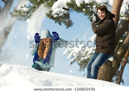 happy young people playing with snow splashes in sunny winter outdoors