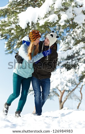 happy young smiling adult people in warm clothing walking in snowy forest at winter outdoors