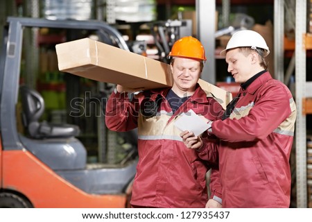 two store workers man in uniform in front of warehouse forklift loader discussing order