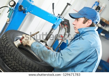 serviceman repairman worker lubricating car tyre at workshop befor fitting
