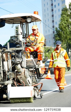 two construction workers with roaad marking machine at asphalt road pavement markings