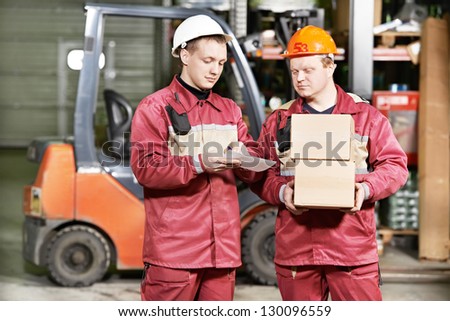 young warehouse workers in uniform in front of forklift stacker loader