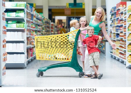 Family shopping. Woman and children with shop cart in supermarket store