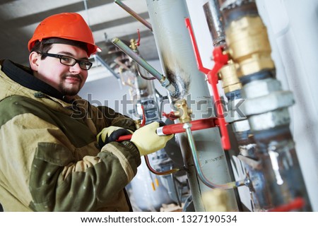 industrial plumber assembling pipes, valves, faucets in water circulation room